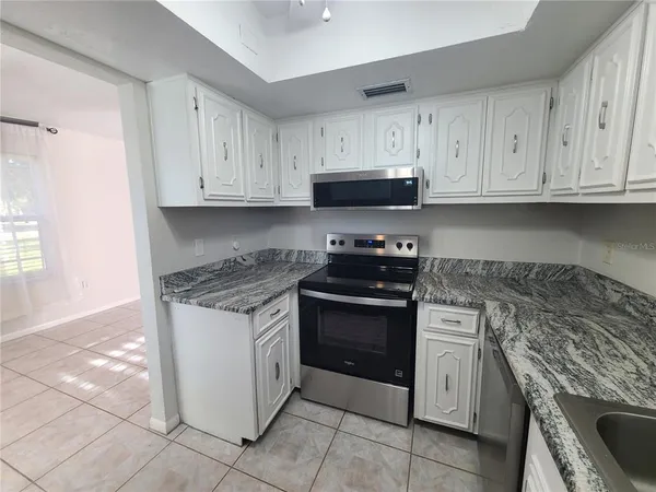 a kitchen with granite countertop a stove sink and cabinets