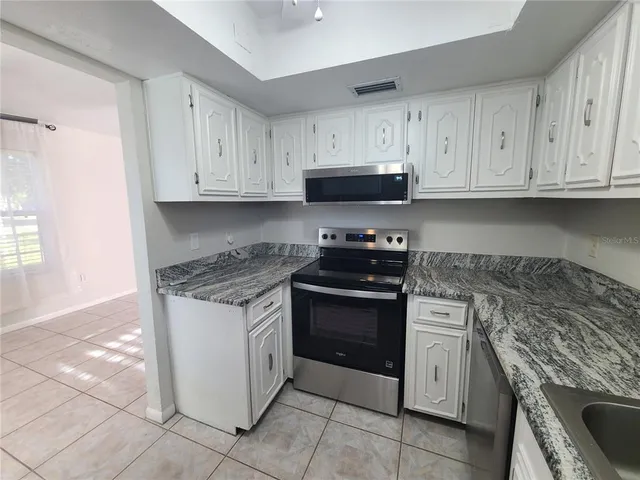 a kitchen with granite countertop a stove sink and cabinets