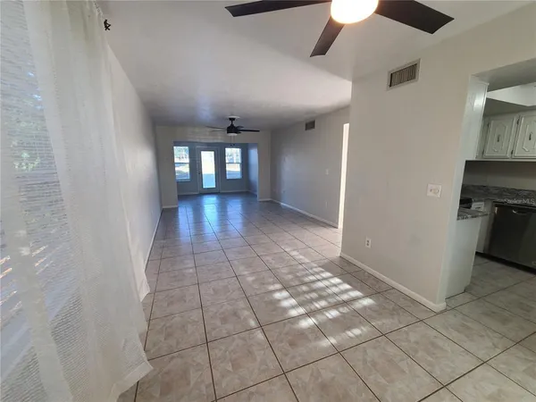 a view of an empty room with window and chandelier fan