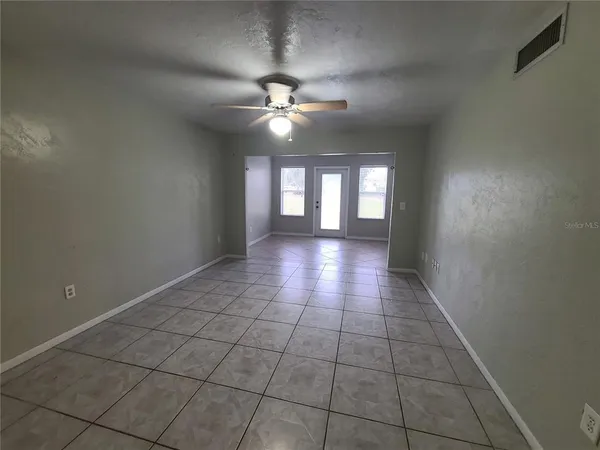 a view of an empty room with a chandelier fan