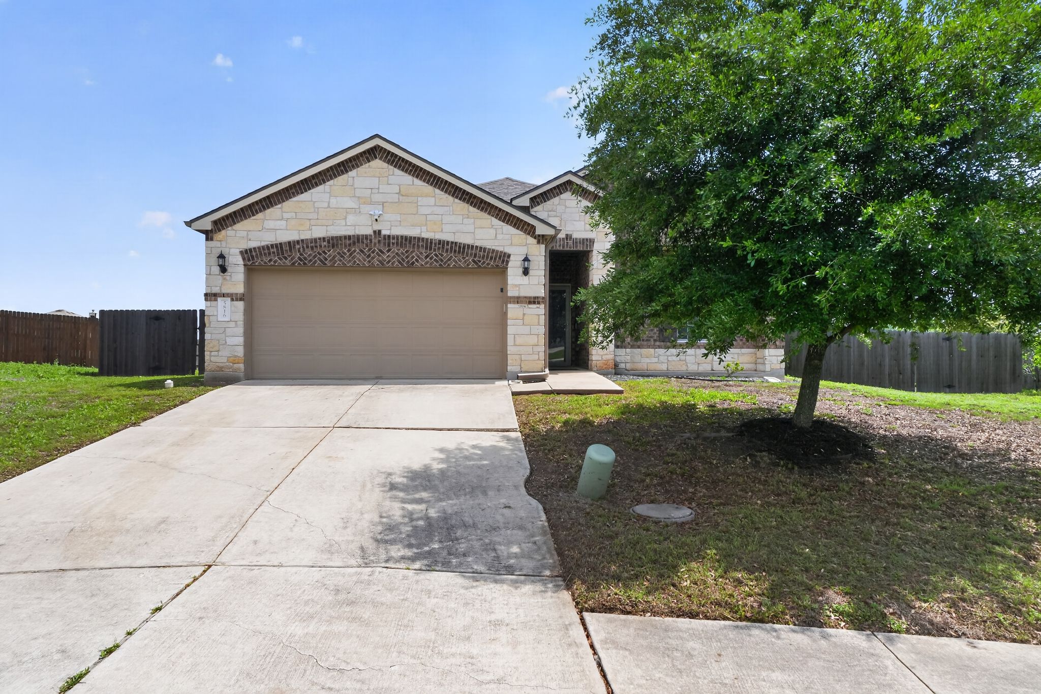 5816 Minch Road Austin, TX 78754 - Photo 1 of 15 The property features a stone and brick facade, a two-car garage, and a concrete driveway