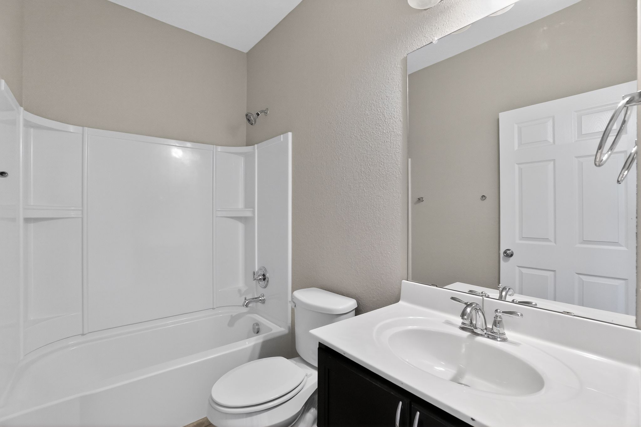 5816 Minch Road Austin, TX 78754 - Photo 11 of 15 Bathroom with a white bathtub and shower surround, a white toilet, and a vanity with a white countertop and dark cabinetry