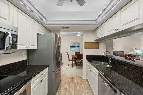 a kitchen with granite countertop stainless steel appliances a sink stove top oven and cabinets