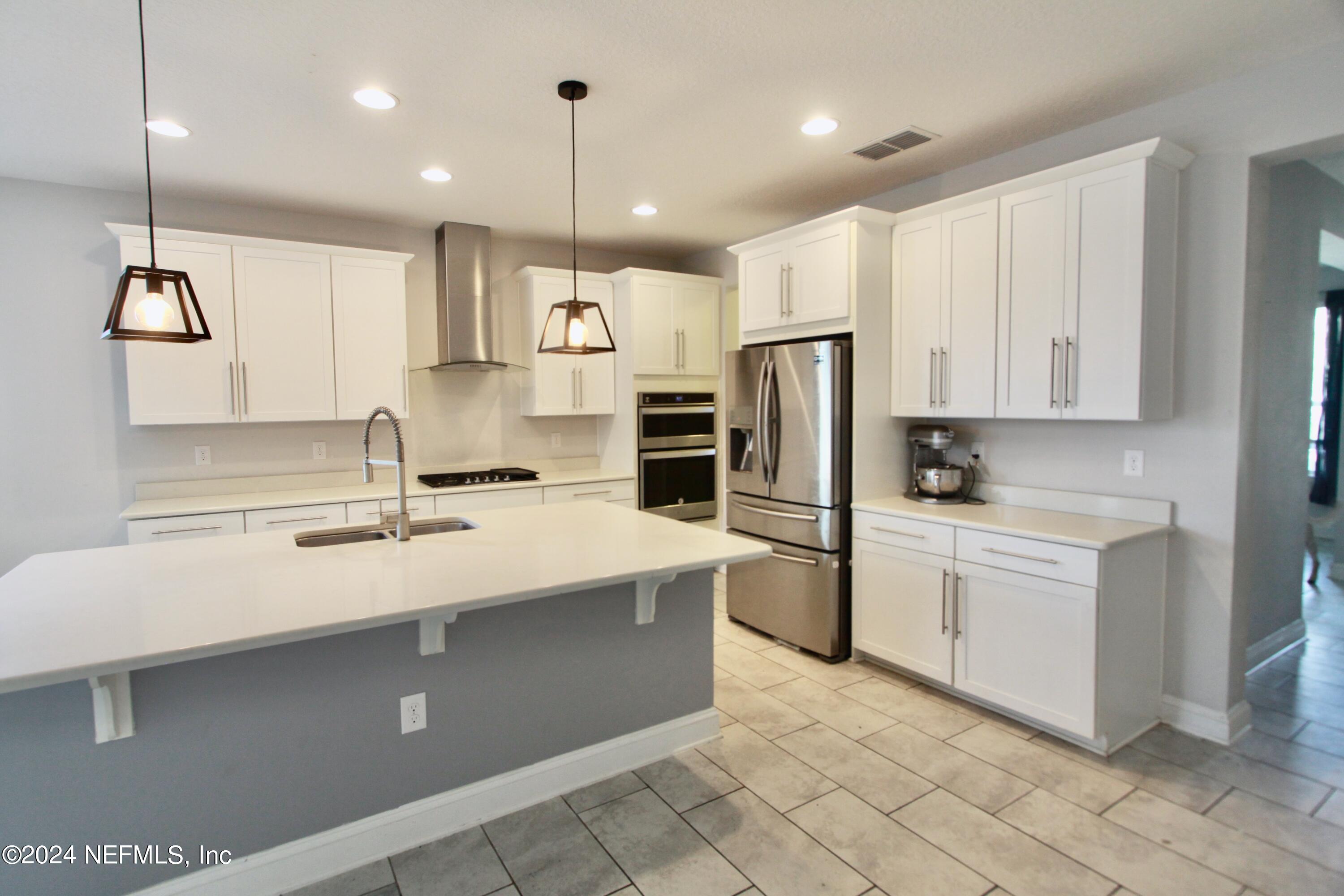 458 Convex Lane St. Augustine, FL 32095 - Photo 4 of 26 a kitchen with stainless steel appliances kitchen island a sink a stove a refrigerator and white cabinets