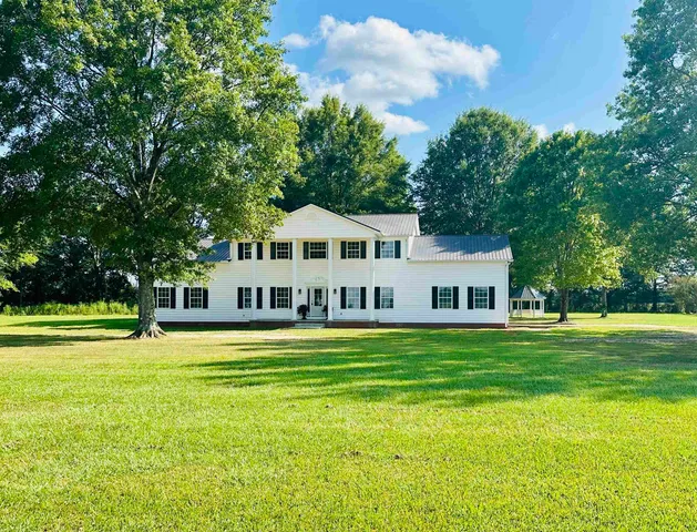 a front view of a house with a yard and trees