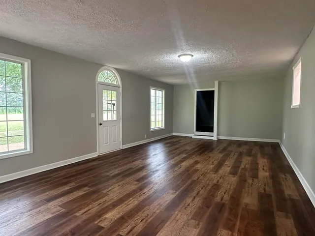 an empty room with wooden floor and windows