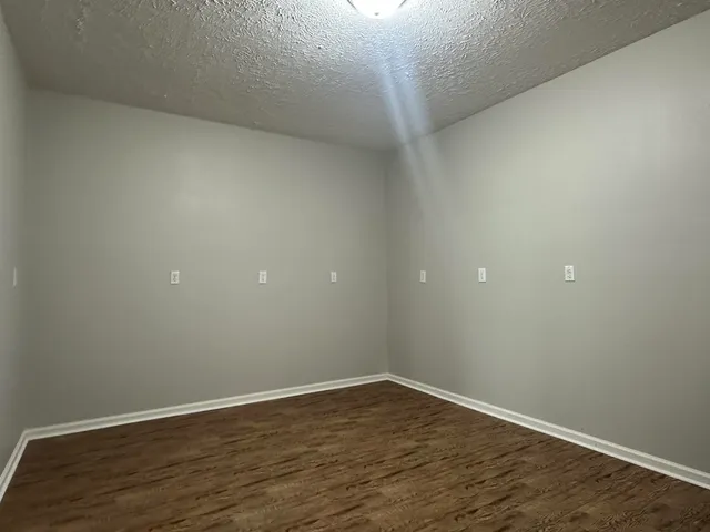 a view of an empty room with wooden floor and bathroom