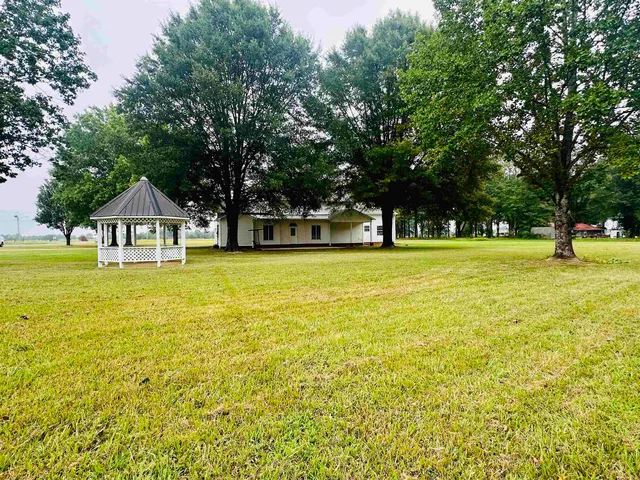 a view of pool with lawn chairs and large trees