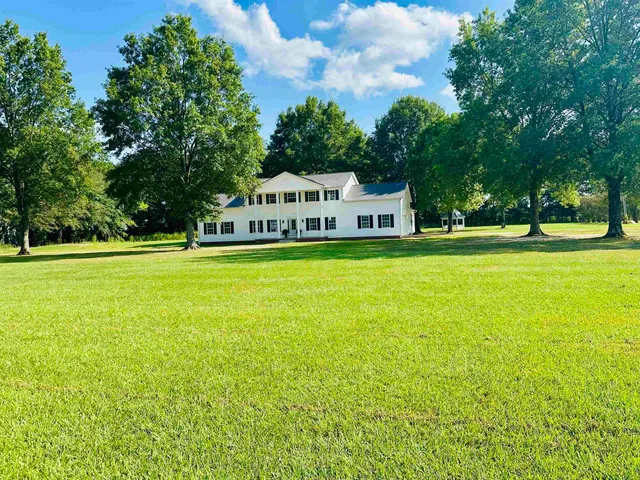 a view of a house with a big yard and large trees