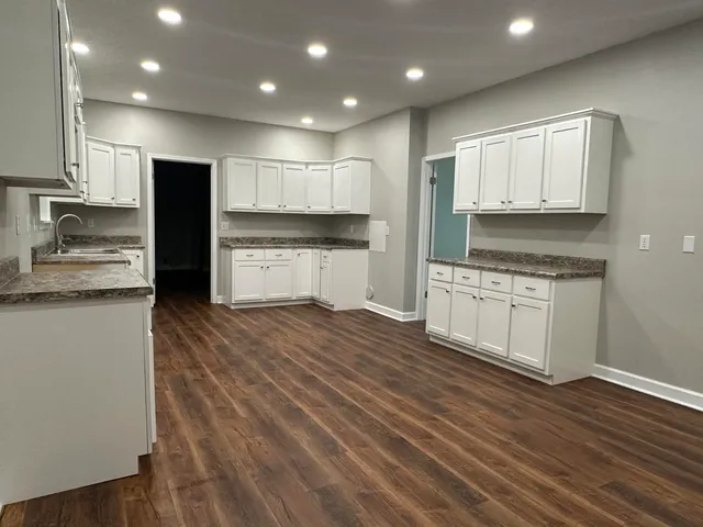 a large kitchen with stainless steel appliances granite countertop a stove a sink and white cabinets