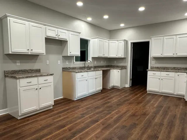 a kitchen with stainless steel appliances granite countertop a stove a sink and white cabinets