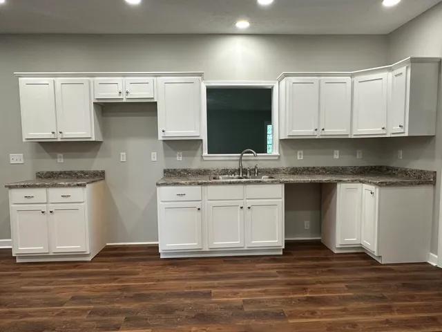a kitchen with granite countertop a sink cabinets and stainless steel appliances