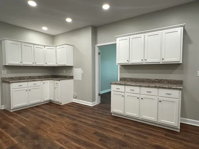 a kitchen with granite countertop white cabinets and white appliances