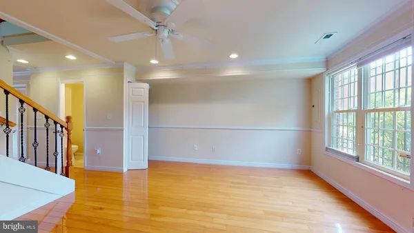 a view of an empty room with window and wooden floor