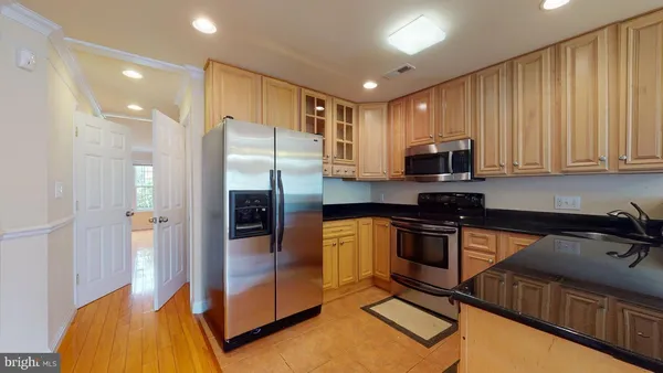 a kitchen with stainless steel appliances granite countertop a refrigerator a stove and a sink with wooden cabinets