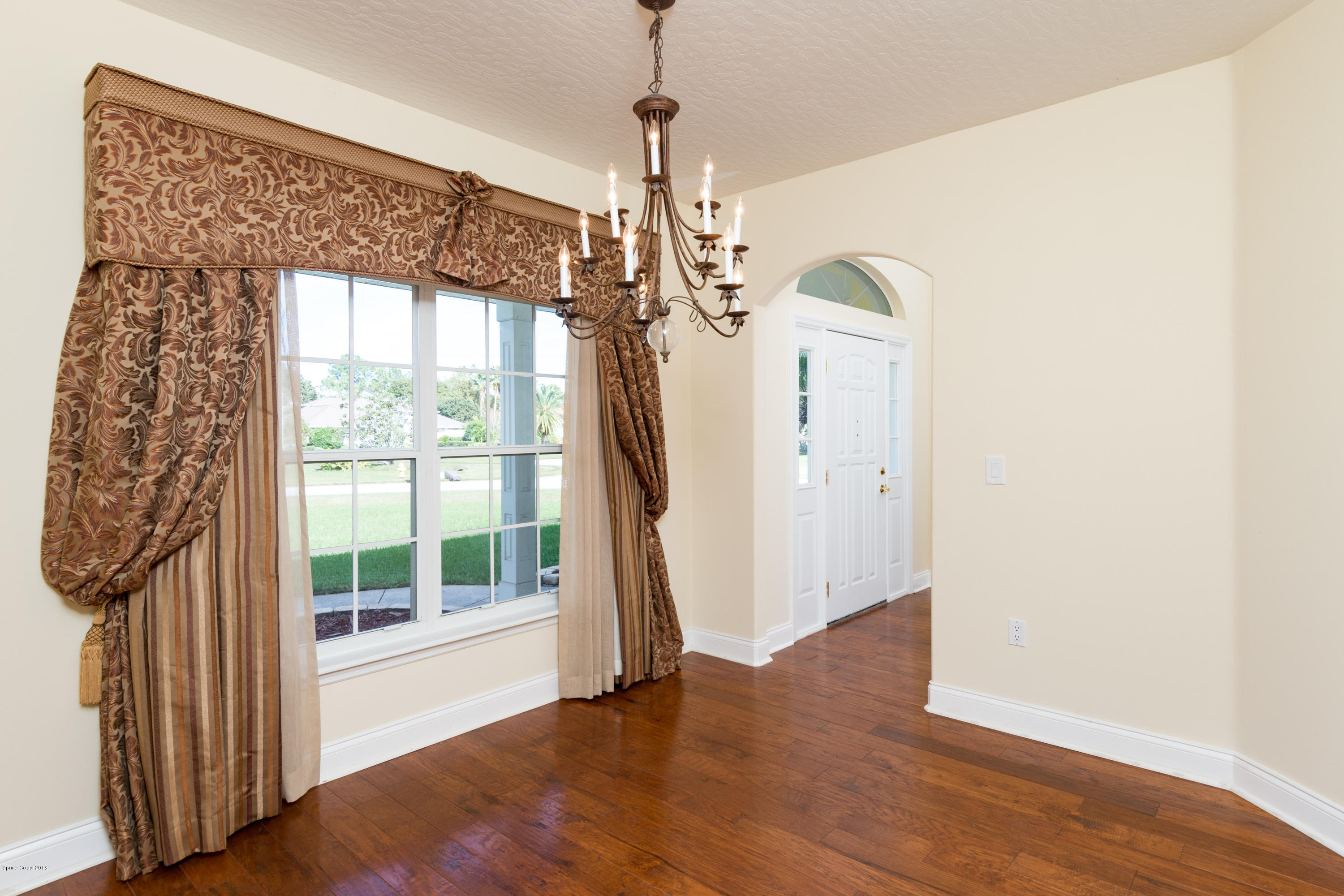 3420 Shady Run Road Melbourne, FL 32934 - Photo 12 of 33 a view of a hallway with wooden floor and a chandelier