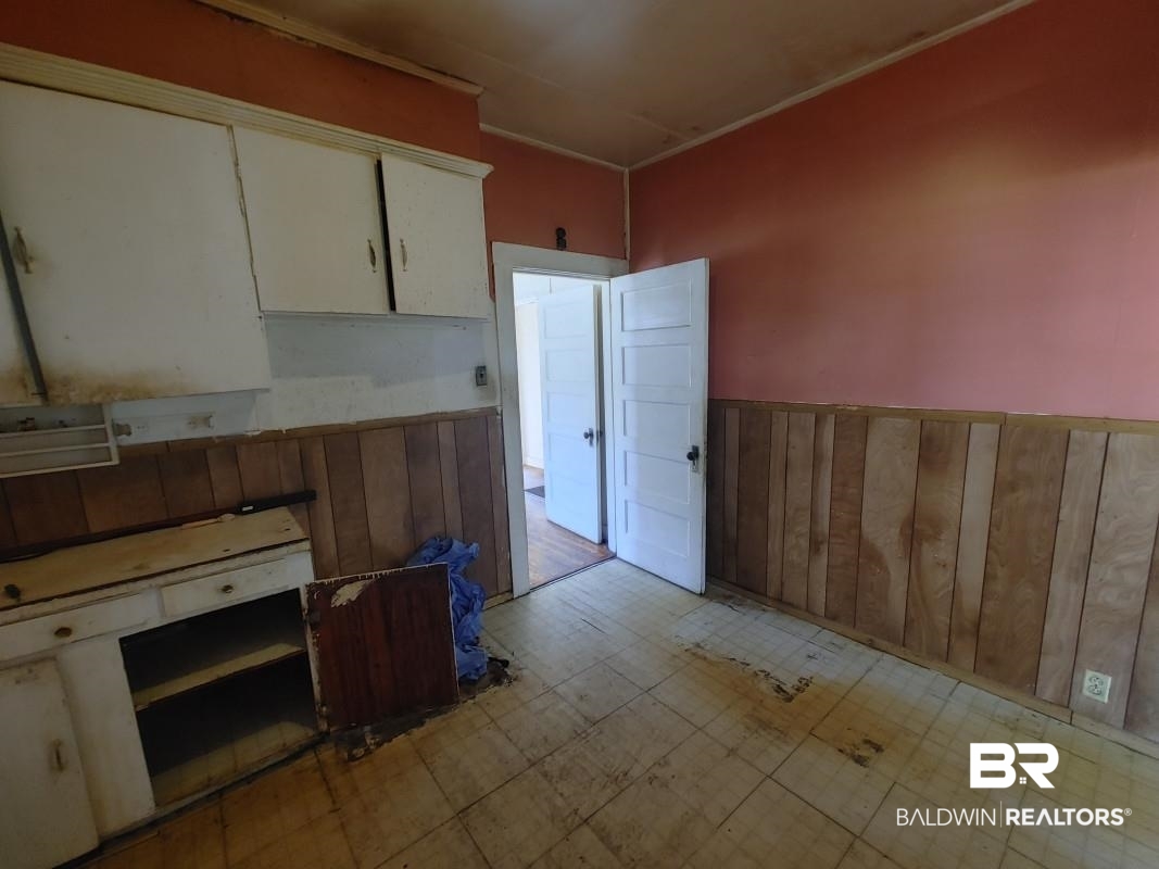 1706 Lomeroy Street Mobile, AL 36604 - Photo 21 of 24 Kitchen with a wainscoted wall, wooden walls, white cabinets, and light floors
