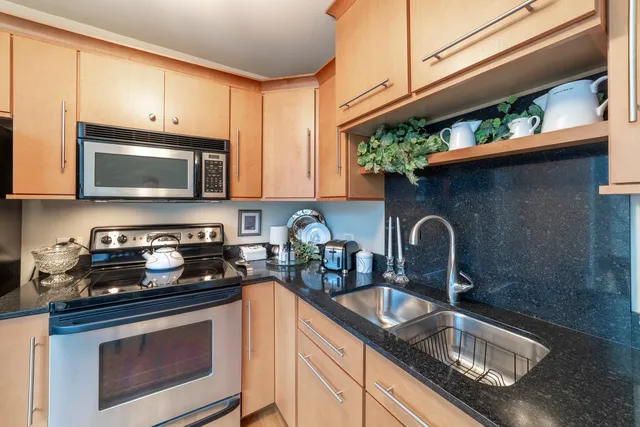 a kitchen with stainless steel appliances granite countertop a sink a stove and a microwave