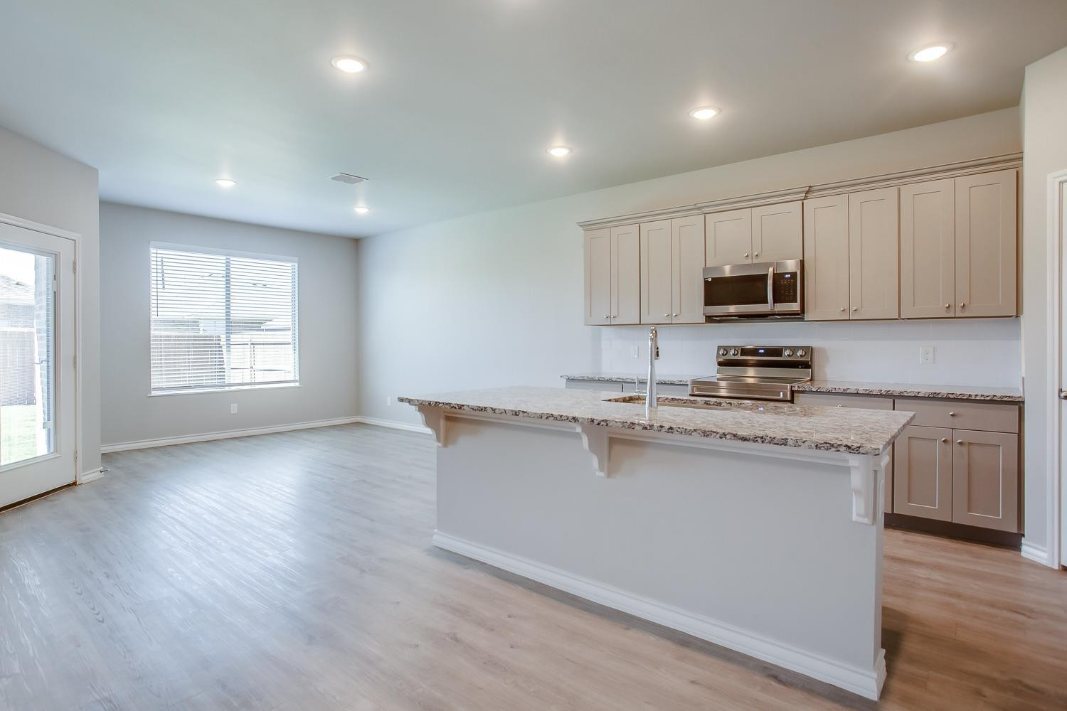 5804 Winfield Avenue Lubbock, TX 79407 - Photo 6 of 18 a kitchen with stainless steel appliances granite countertop a stove a sink a refrigerator white cabinets and a wooden floor