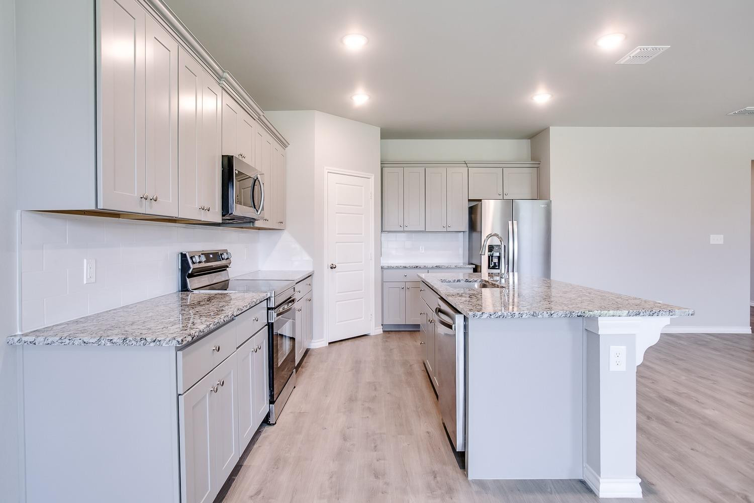5804 Winfield Avenue Lubbock, TX 79407 - Photo 7 of 18 a kitchen with kitchen island granite countertop a sink stove and refrigerator