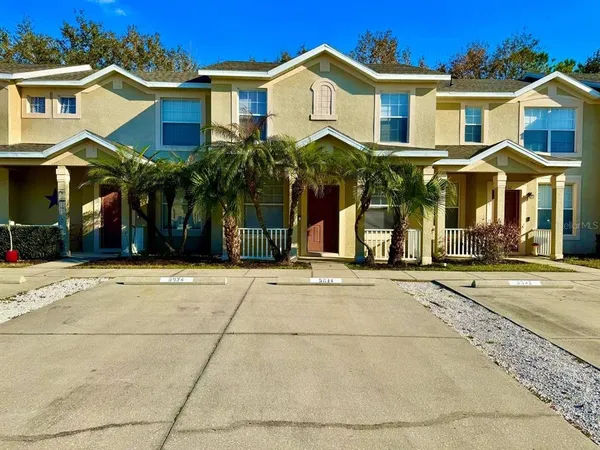 a view of a white house with a clock on the side of a road