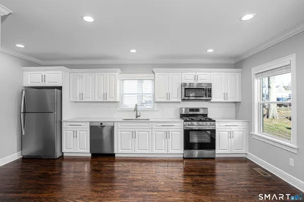 a kitchen with stainless steel appliances granite countertop a stove top oven a refrigerator a sink and a microwave