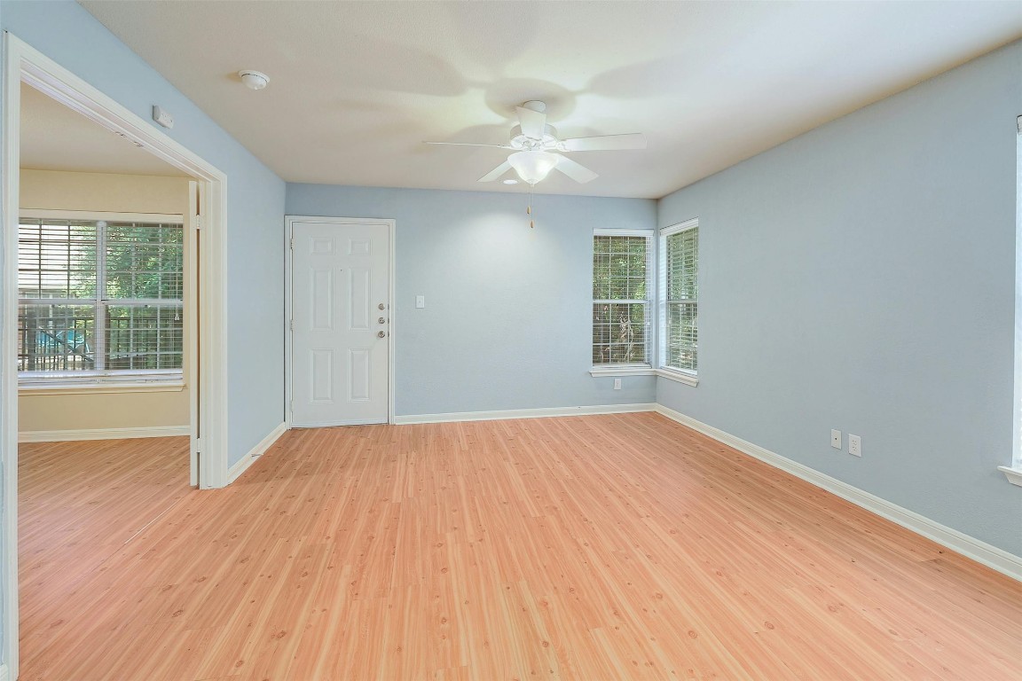 a view of an empty room with wooden floor and a window