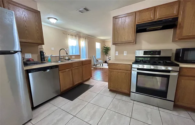 a kitchen with stainless steel appliances granite countertop a stove a sink and a microwave