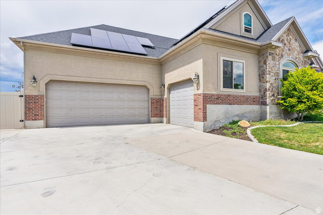 316 Azure Circle Draper, UT 84020 - Photo 8 of 48 Stucco and stone exterior featuring a two-car garage, single-car garage, and solar panels