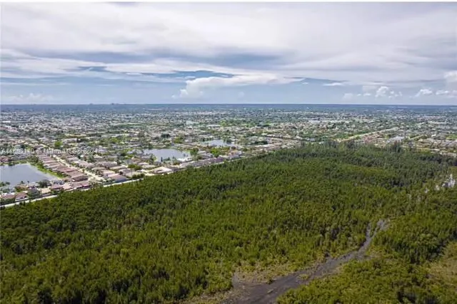 an aerial view of residential houses with outdoor space and trees