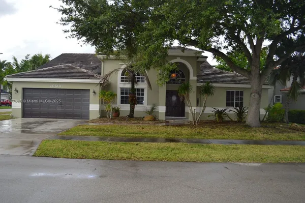 a front view of a house with a garden and trees
