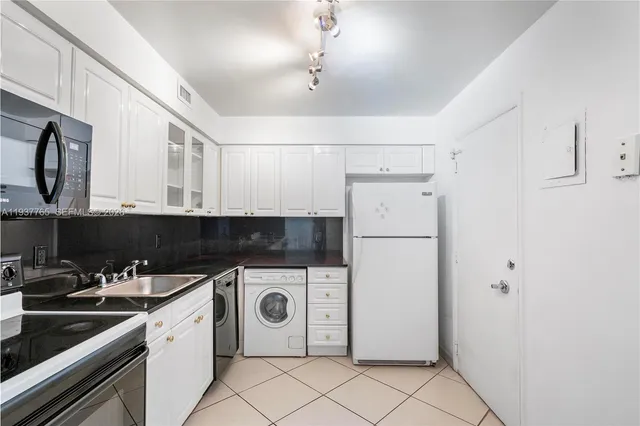 a kitchen with a sink a refrigerator and cabinets