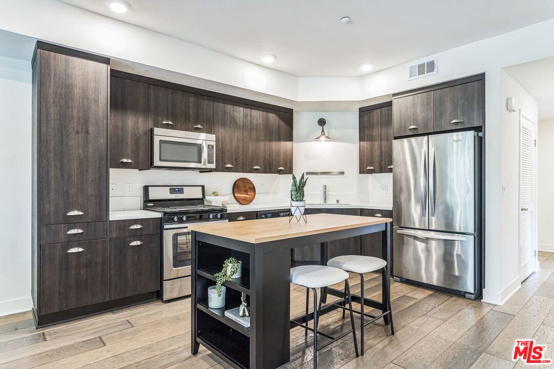 2976 Ripple Place, Unit 103 Los Angeles, CA 90039 - Photo 10 of 16 a kitchen with kitchen island a refrigerator stove and microwave