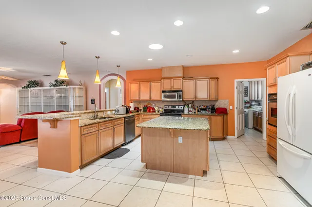 a kitchen with stainless steel appliances granite countertop a refrigerator a sink and a stove