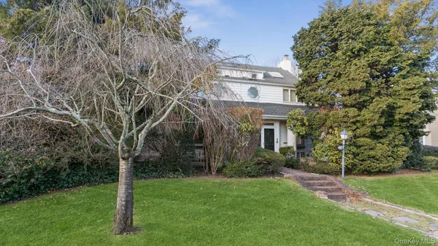 a view of a brick house next to a yard with large trees