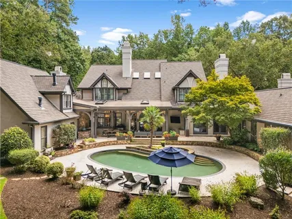 a view of a house with swimming pool lawn chairs and a yard