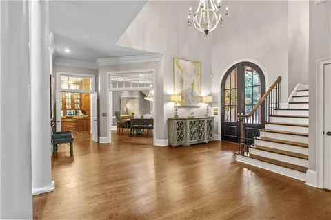 a dining room with wooden floor a chandelier a wooden table and chairs