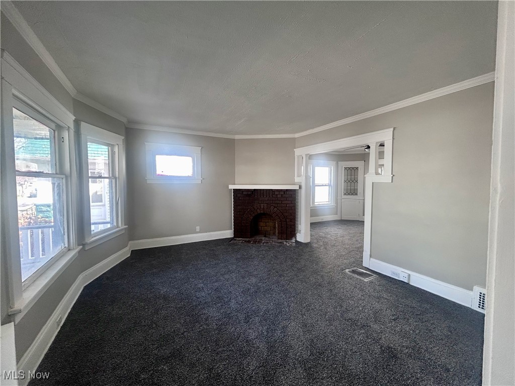 13412 Graham Road Cleveland, OH 44112 - Photo 3 of 18 Unfurnished living room with dark colored carpet, ornamental molding, and a wealth of natural light