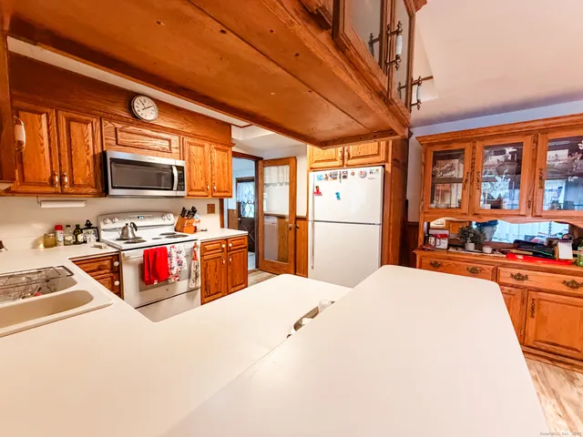 a kitchen with stainless steel appliances kitchen island granite countertop a refrigerator a stove top oven a sink dishwasher and white cabinets with wooden floor