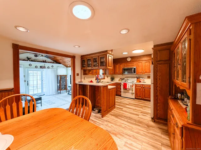 a open kitchen with stainless steel appliances kitchen island granite countertop a refrigerator a stove top oven and a sink with wooden floor