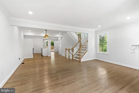 an empty room with wooden floor windows and a chandelier