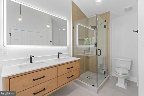 a bathroom with a double vanity sink toilet mirror and shower