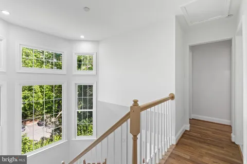 a view of a hallway with wooden floor and windows