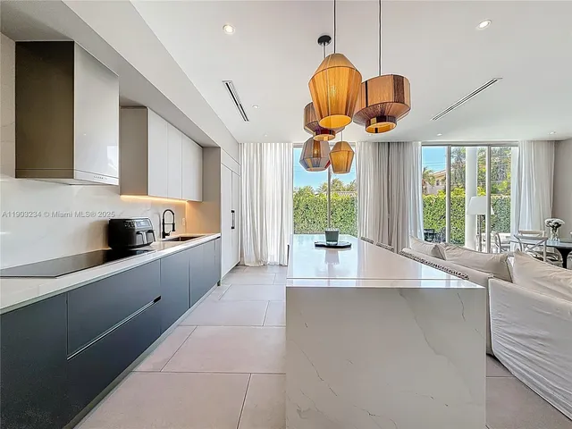 a large kitchen with stainless steel appliances a large counter top a stove and a sink