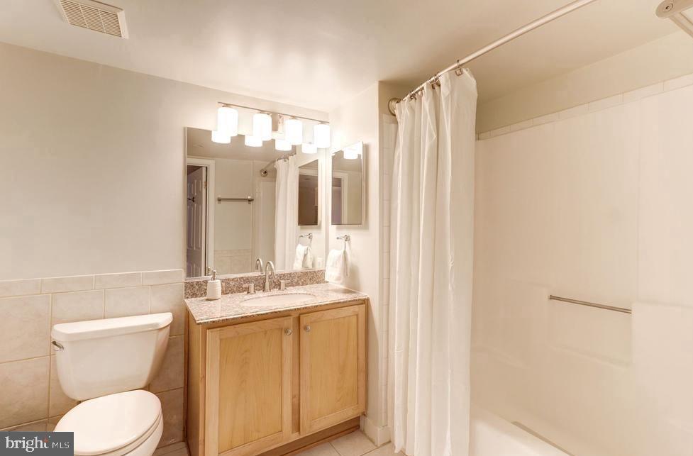 1001 North Randolph Street, Unit 406 Arlington, VA 22201 - Photo 10 of 23 a bathroom with a granite countertop sink toilet and shower