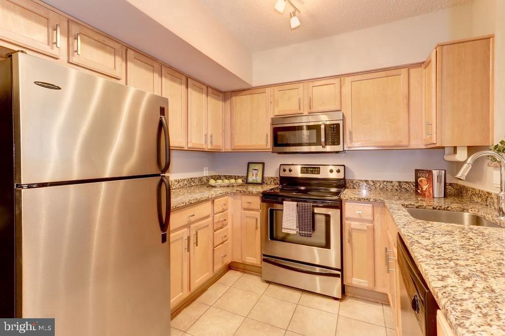 1001 North Randolph Street, Unit 406 Arlington, VA 22201 - Photo 4 of 23 a kitchen with stainless steel appliances granite countertop a refrigerator a stove a sink and a microwave