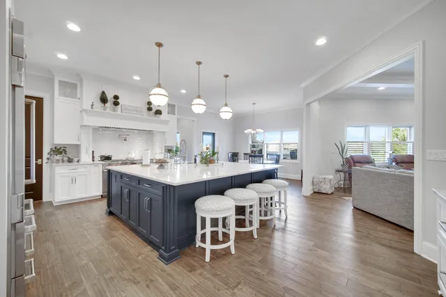 a kitchen with stainless steel appliances granite countertop a stove a oven a dining table and chairs with wooden floor