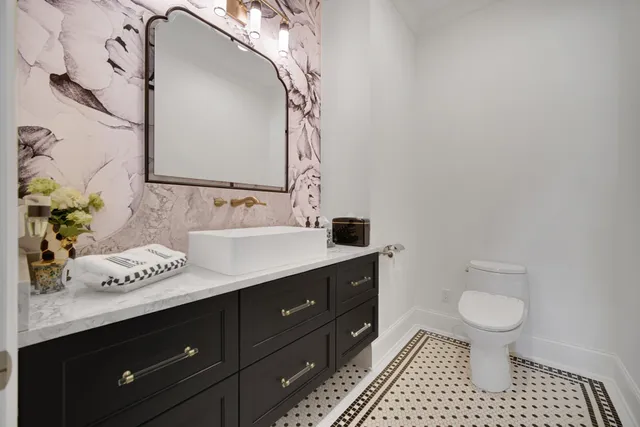 a large white kitchen with a stove a sink dishwasher a dining table and chairs with wooden floor