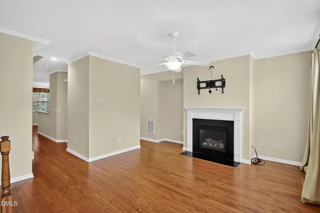 a view of an empty room with wooden floor fireplace and a window