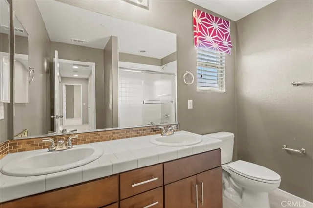 a bathroom with a granite countertop sink a toilet and a mirror